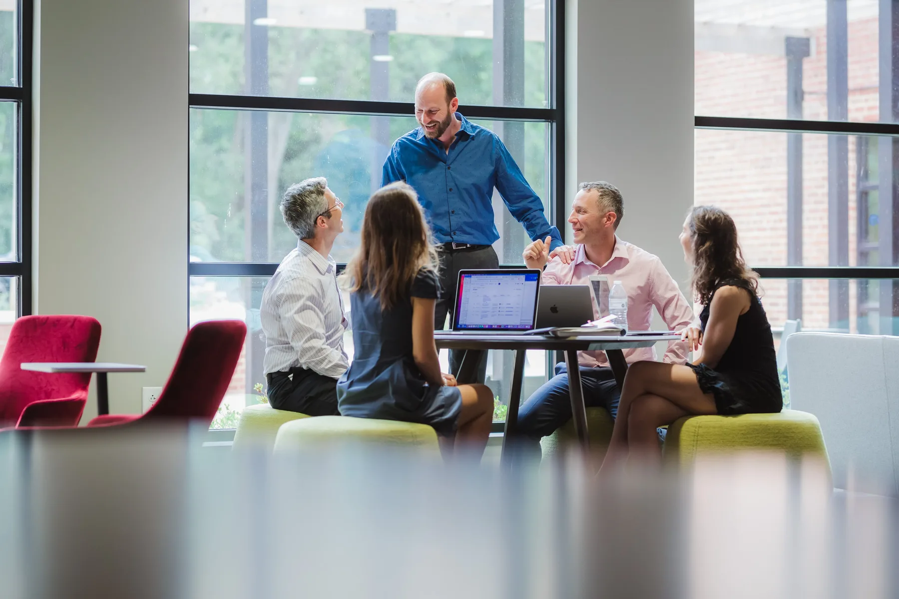 An Everblue team meeting around a laptop in a bright lounge.