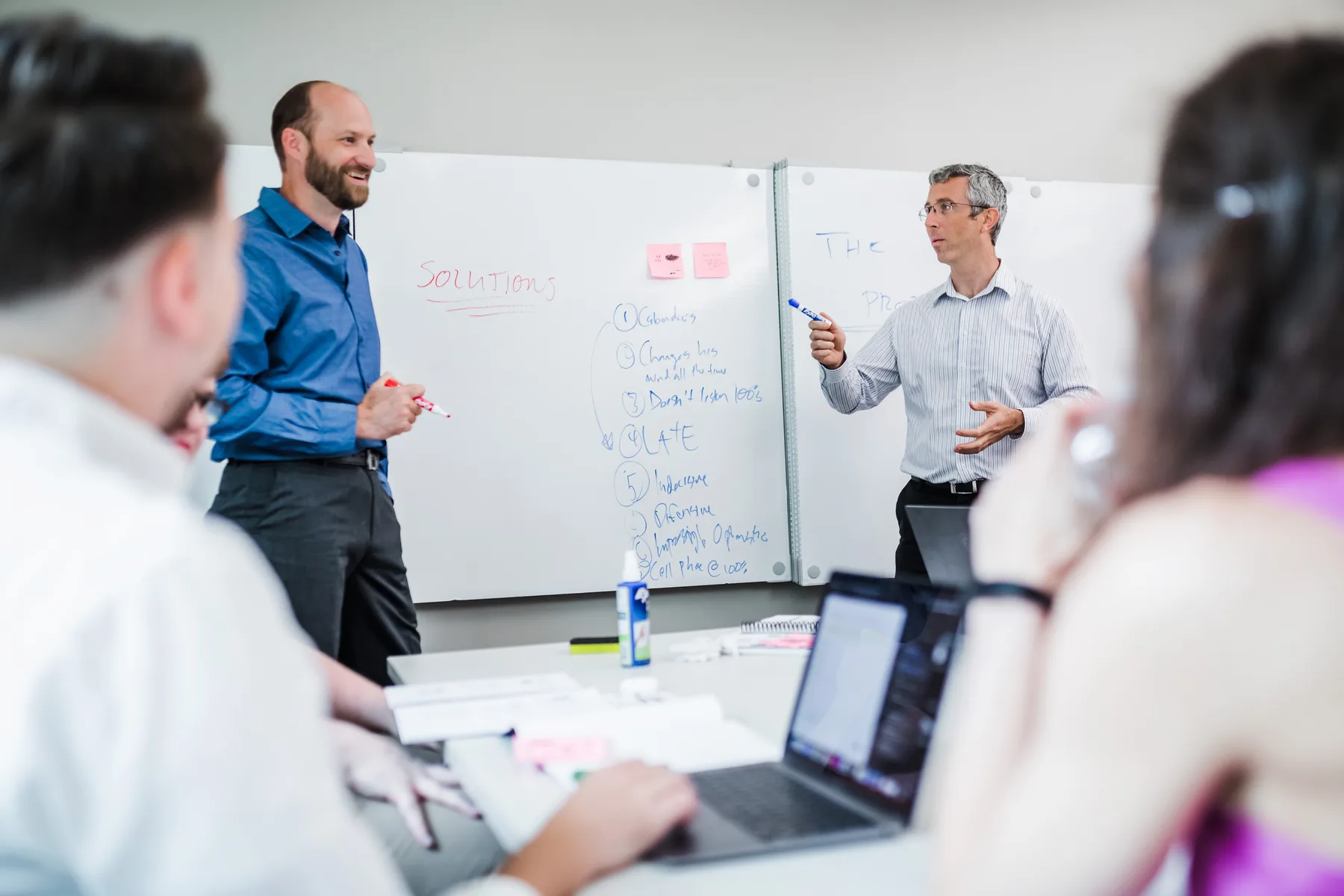 Two Everblue team members working through a program plan at a whiteboard.